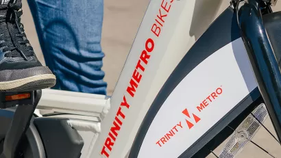 Close-up of person wearing Nike tennis shoe on Trinity Metro bike share e-bike.