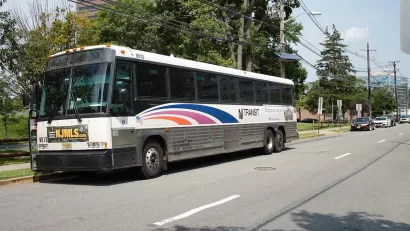 White NJ Transit parked at station with blue stripes.