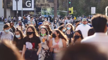 Large numbers of young people, some wearing and masks and others note, walk around an outdoor shopping mall in Southern California.