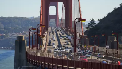 The Golden Gate bridge viewed from Marin, with cars passing in either direction on a sunny day.