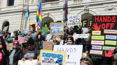 Crowd gathered with protest signs on April 5, 2025 on steps of Minnesota state capitol protesting Trump cuts to social security and other federal programs.