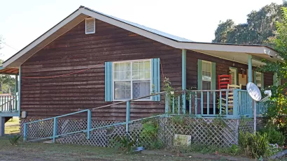 Side view of a wooden-sided house with sky-blue shutters.