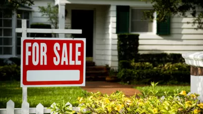 White clapboard house with For Sale sign in front yard