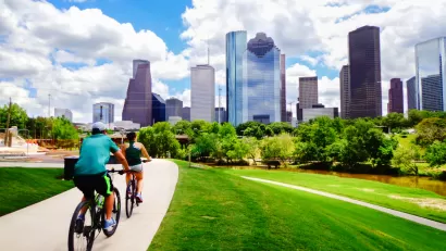Two people on a bike trail with downtown Houston in the background