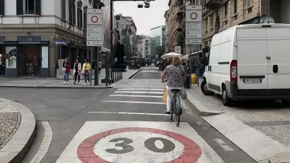 A bike rider navigates a bike lane in a traffic limited zone in Italy, where only one delivery van is visible on the street.