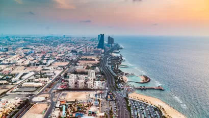 An aerial view down the length of the Jeddah coastline in Saudi Arabia, showing coastal developments, beaches, and a few high-rise buildings along the shoreline.