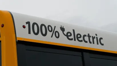 Close-up of white panel at top of school bus with "100% electric" black text.