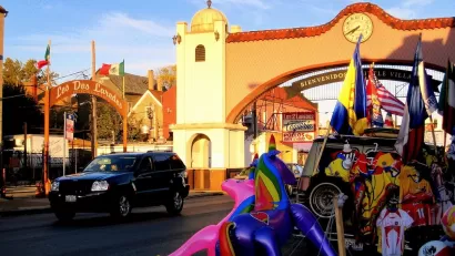Spanish-style arch over street reading 'Bienvenidos a Little Village" in Chicago, Illinois at golden hour.