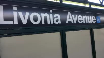 Close-up of black and white Livonia Avenue subway sign with blue accessibility symbol