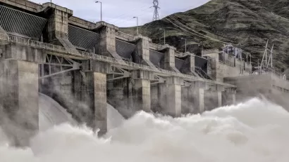 Water rushes over a spillway at a large concrete dam.