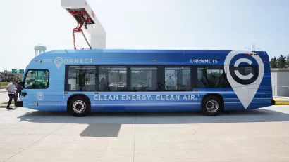 Blue electric MCTS bus sits at a charging station