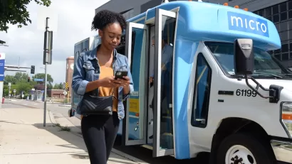 Girl walking in front og blue and white minibus with 'micro' logo in Minneapolis, Minnesota.
