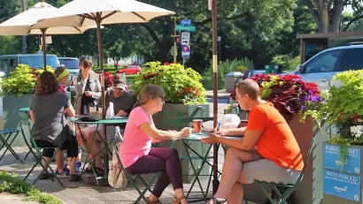 People sitting at small tables in a public parklet in Minneapolis, Minnesota.
