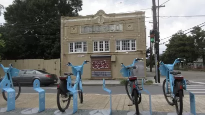 Row of blue Blue Bikes bike share bikes at docked station on sidewalk in New Orleans, Louisiana.
