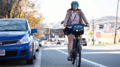 Woman wearing helmet riding POGOH bike share bike in bike lane in Pittsburgh, PA.