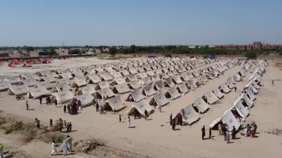 A humanitarian facility, with rows of tents, is set up in a dusty field in Pakistan.