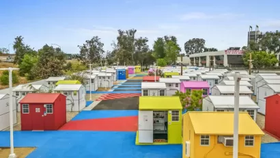 Multicolored tiny homes for temporary shelter in complex adjacent to freeway overpass in Los Angeles, California.