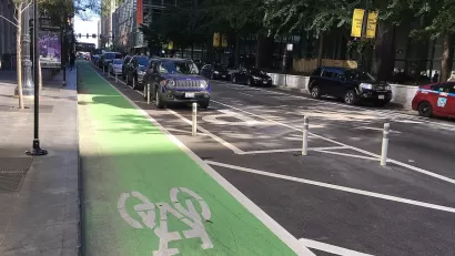 Green painted bike lane protected by rown of parking.