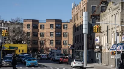 Large silver pole on street corner in LA, nearly same height as surrounding three-story buildings.