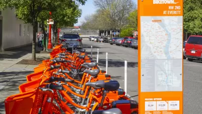 Numerous orange Portland Biketown bikes are parked at a facility in Northwest Oregon.
