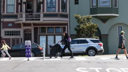 People walking on San Francisco street with 'Slow Streets' signs.