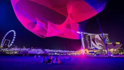 Pink light art installation above public plaza in Singapore by Janet Echelman.