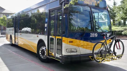 White and blue Sacramento regional transit bus with one bike on front bike rack.