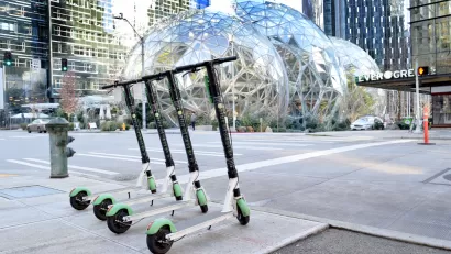 A row of Electric Scooter for sharing from Lime in Seattle with the Amazon Spheres in the background.