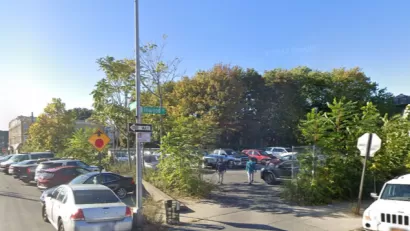 Google street view of vacant lot used for parking and surrounded by chain link fence and shrubbery in East New York