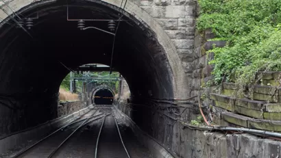 View into gray stone train tunnel with visible opening on other side
