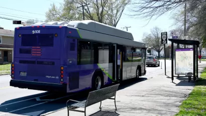 Purple GRTC bus stopped at a bus station with bench and shelter in Richmond, Virginia.
