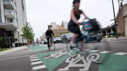 Cyclists riding on green painted bike lane protected by flexible post delineators in Chicago, Illinois.