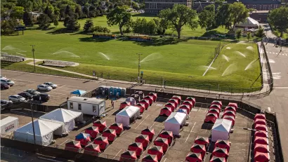 Ice fishing tents surrounded by fence in Safe Outdoor Space for unhoused people in parking lot in Denver, Colorado.
