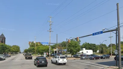 Google street view of wide street in Cleveland, Ohio with blue 55th Street sign and red brick three-story building visible in right corner.