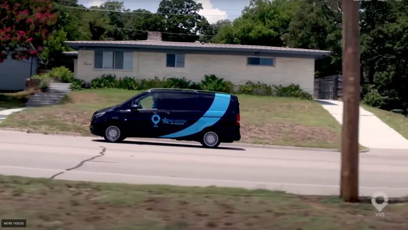 A blue microtransit van drives through Texas
