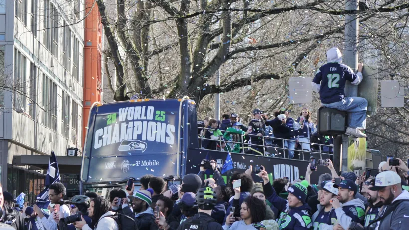 People celebrating at Seattle Seahawks Super Bowl victory parade on street in Seattle.