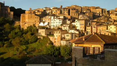 The city of Siena in Italy, located on a hillside and bathed in Tuscan sunlight.