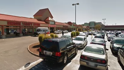 A typical American shopping center, with a thrift store at one end and a parking lot full of cars.