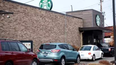 A line of cars wait at the drive-thru window of a starbucks.
