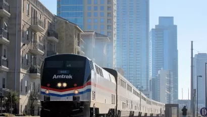Texas Eagle Amtrak train pulling into station in Austin, Texas with glass high-rise buildings in background.