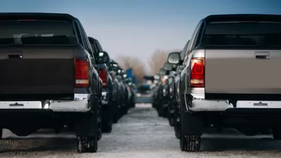 Large pickup trucks are parked in neat rows extending into the fuzzy background of the image.