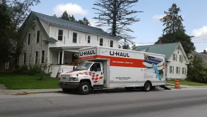U-Haul moving truck in front of white house and trees