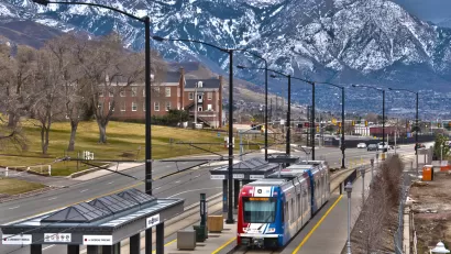 trax light rail train in foreground, snow-covered mountains in background