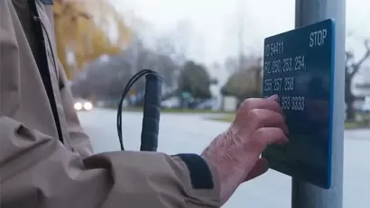 Close-up of hand reading Braille sign at bus stop in Vancouver, British Columbia.