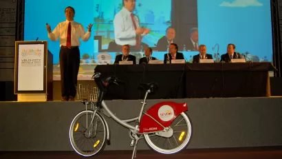 Gil Penalosa speaking on a stage at Velo-city conference in Seville, Spain, with bicycle in foreground