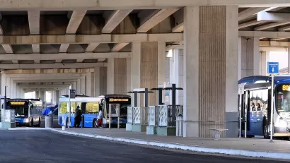 CapMetro buses parked at Westgate Transit Center under freeway overpass in Austin, Texas.