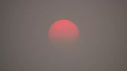 A red sun appears on the horizon, as obscured by haze from wildfire smoke.