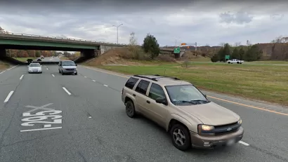 A two-lane highway cuts through a small canyon. The photo is taken from the perspective of a vehicle on the road.