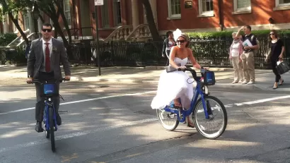 A bride and groom riding on citi bikes in New York