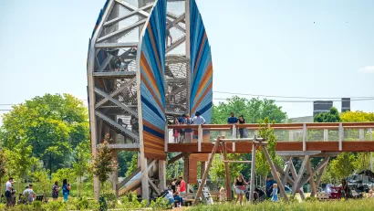 Large wood structure with bridge and people standing on it in green park in Toledo, Ohio.